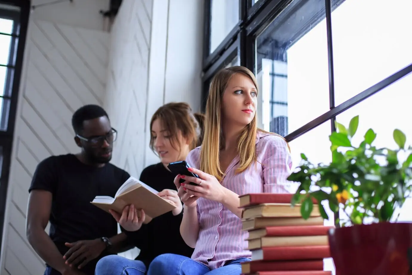 Un hombre negro y dos niñas que leen un libro.